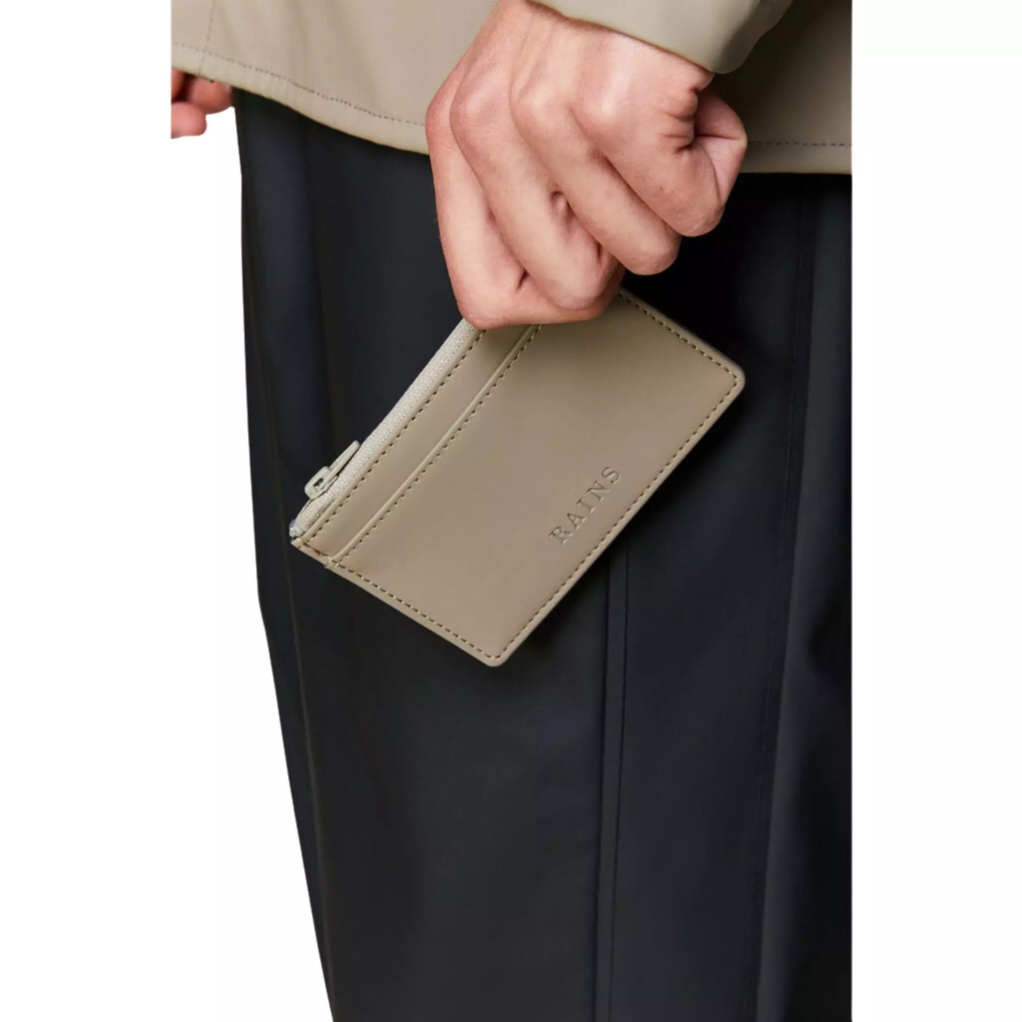Rains waterproof zip wallet taupe held by a man